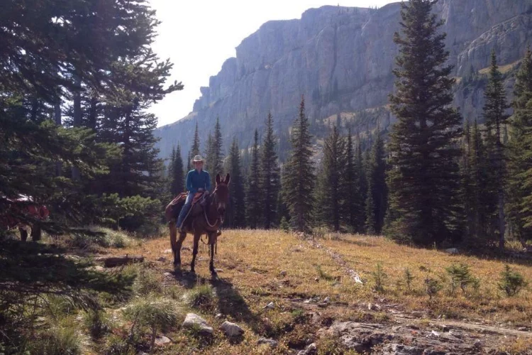 Jeni Garcin, on a mule in front of the Chinese Wall in the Bob Marshall Wilderness.