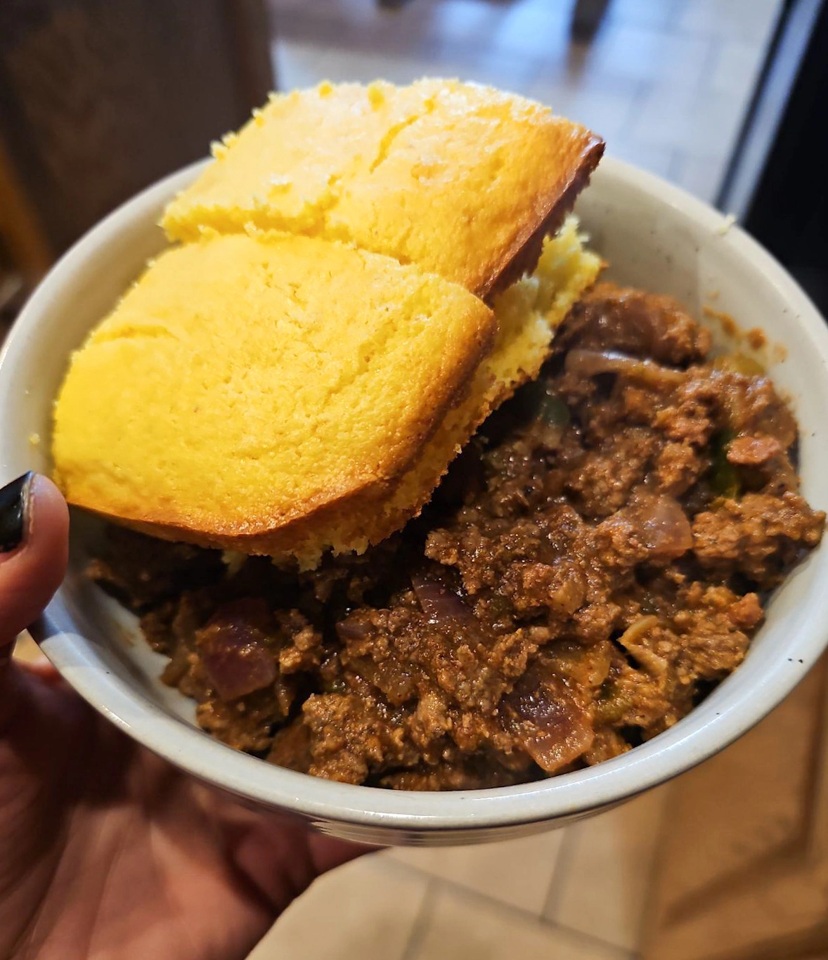 This image shows a bowl full of venison chili with cornbread on the side.