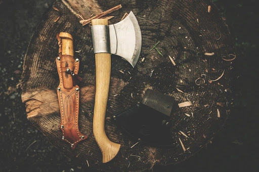 an axe and a knife on tree log